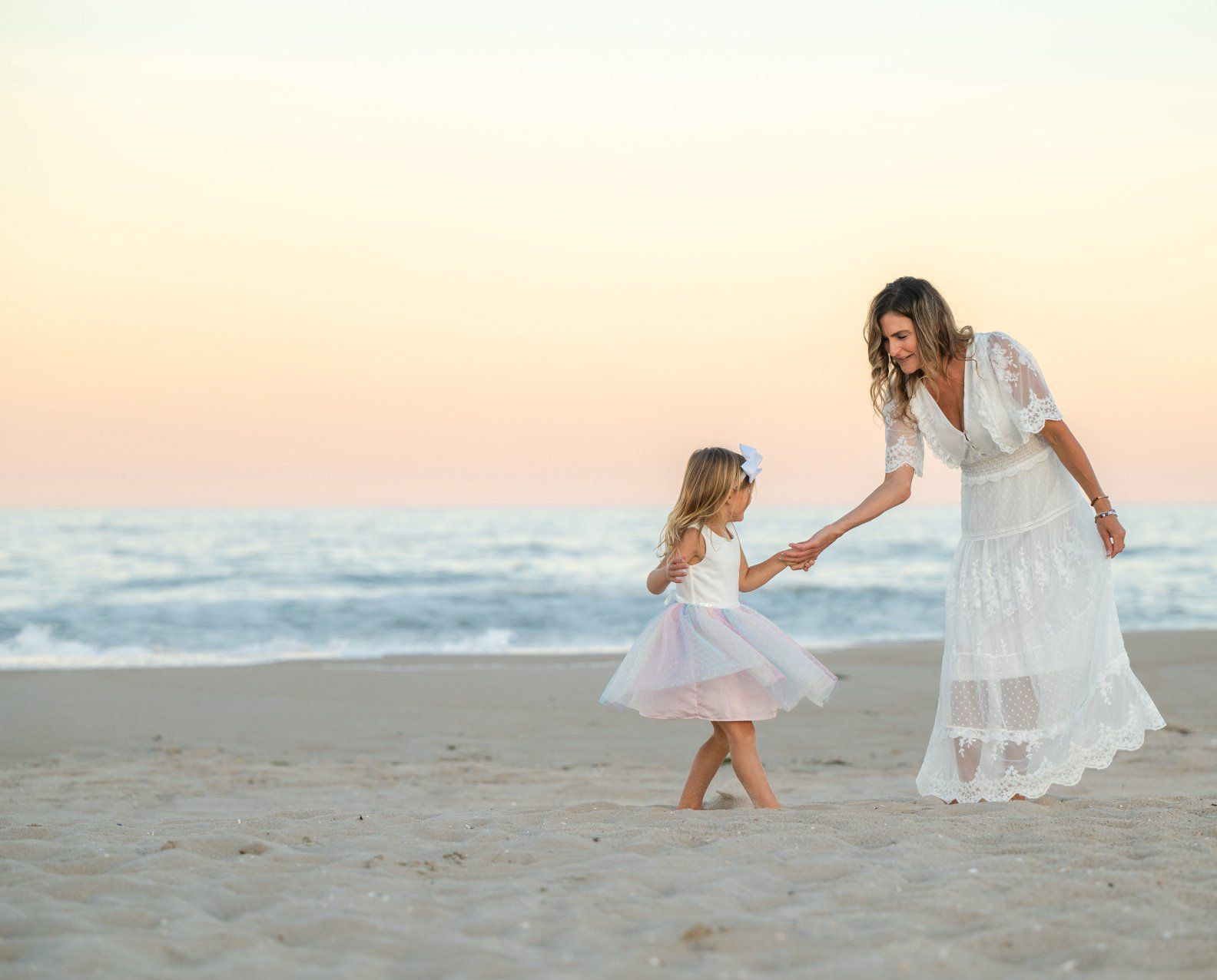 Dr. Kimberly and her young daughter on a beach at sunset.