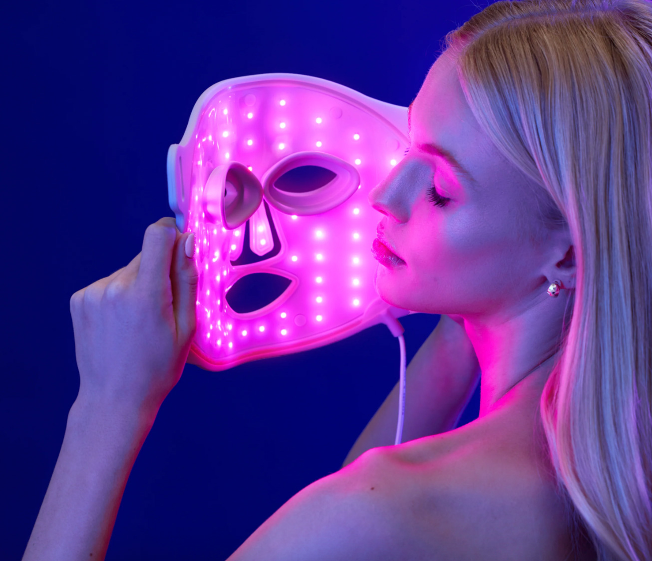 A woman holding a red light therapy mask.